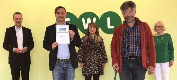 Bild vergr��ern: : Offiziell besiegelt ist die Partnerschaft des EWL bei der Fair-Trade-Bewegung in Landau. Christin Arto, J�rgen Leonhard und Barbara Weyrauch, Mitglieder der Steuerungsgruppe �berbrachten die Urkunde stellvertretend an Dr. Maximilian Ingenthron (links) und Falk Pfersdorf (mit Urkunde).